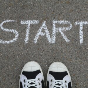 Close-up of sneakers and a 'START' chalk drawing on pavement, symbolizing new beginnings.