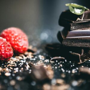 Artistic close-up of dark chocolate pieces with fresh raspberries, perfect for dessert visuals.